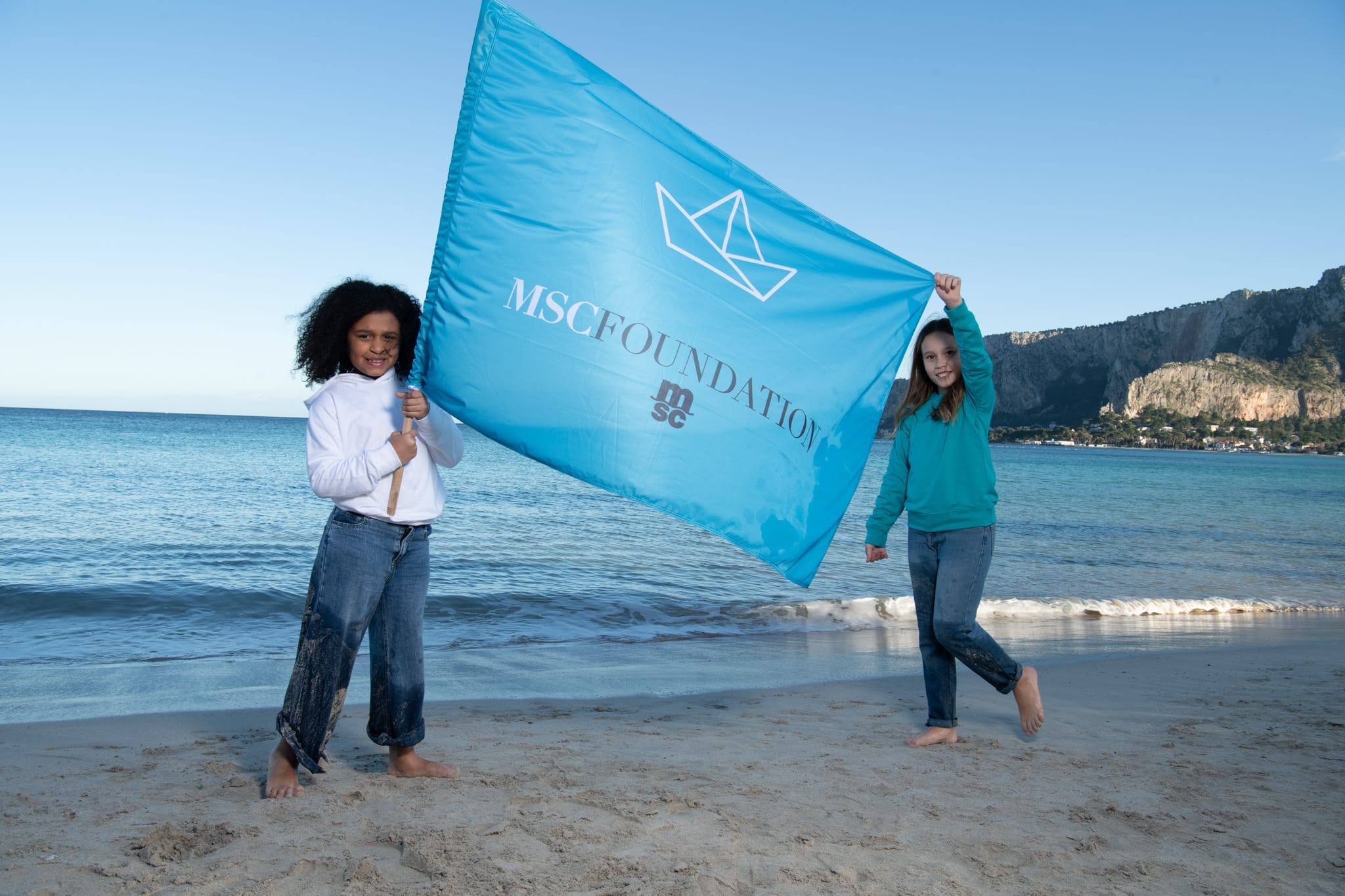 Children holding MSC Foundation flag on the beach