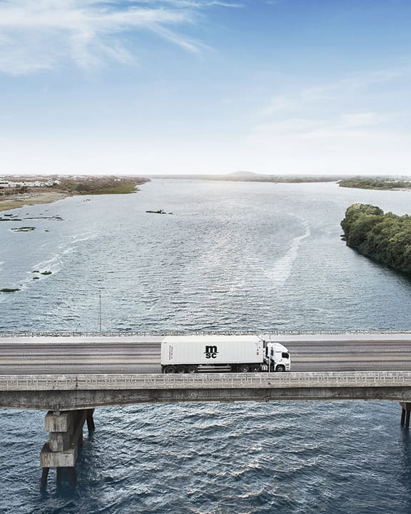 Truck on a bridge carrying a MSC reefer container