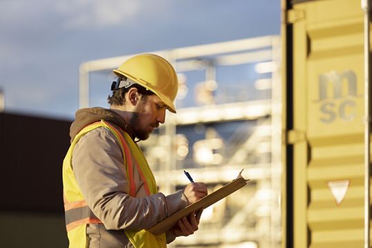 Customs officer inspecting an MSC shipping container and completing clearance paperwork at the terminal.