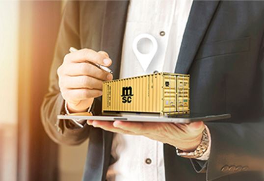 Person in business attire holding a digital model of an MSC smart container on a tablet.