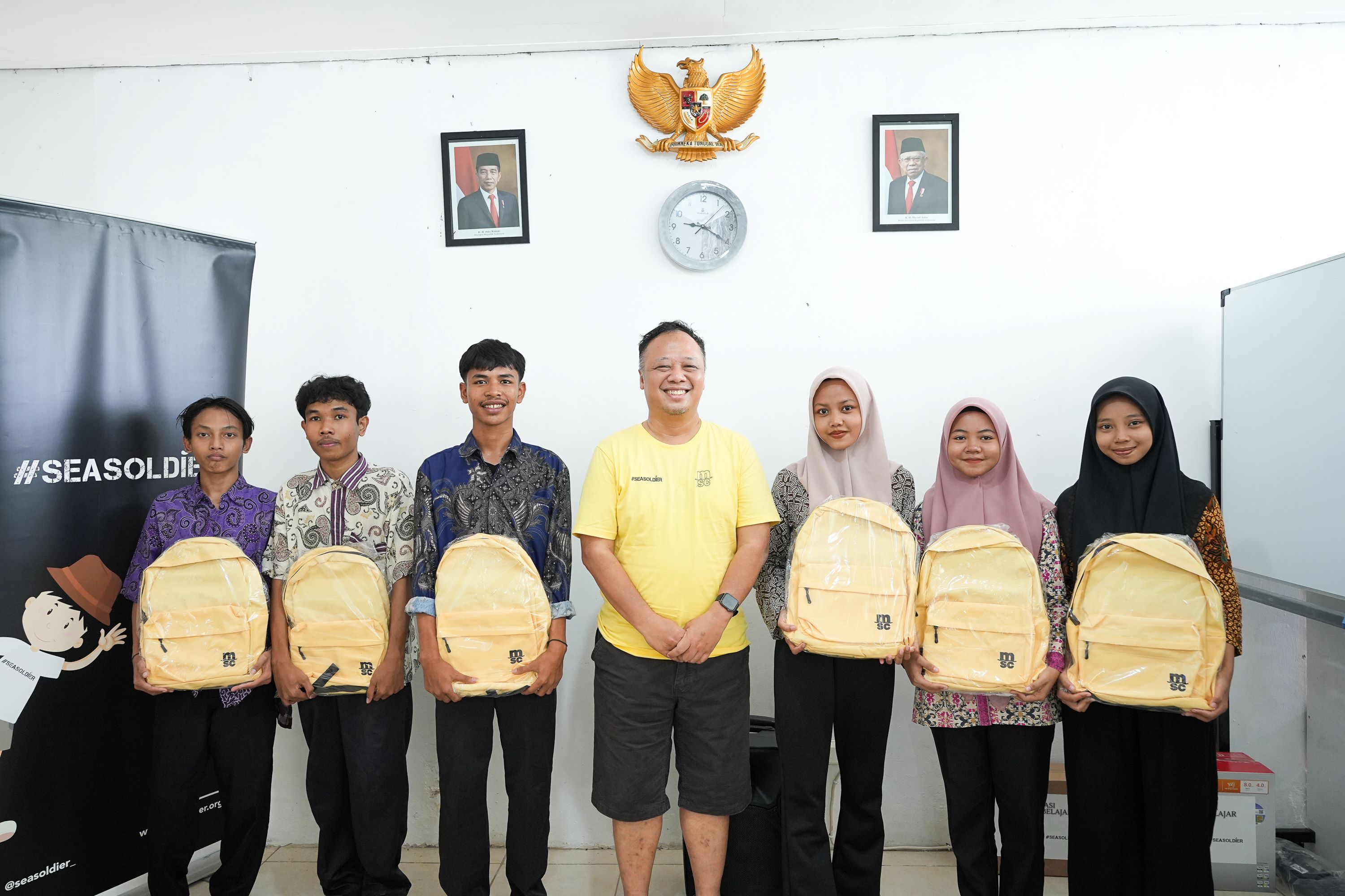 MSC Indonesia employees standing side by side holding yellow bags and smiling